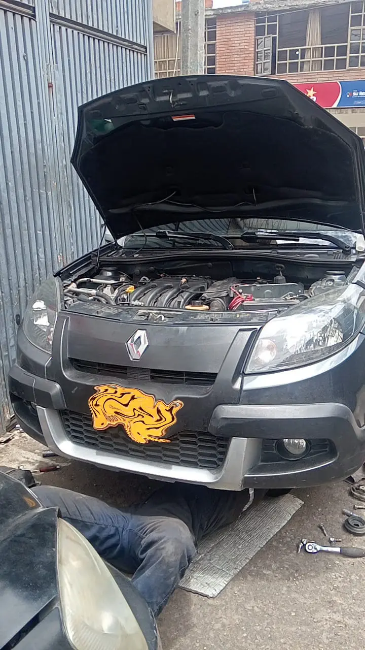 Mecánico del taller trabajando debajo de una Renault Sandero con el capó abierto